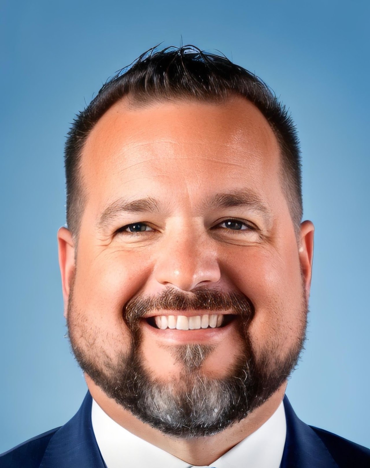 Daniel Able smiling, wearing a navy suit